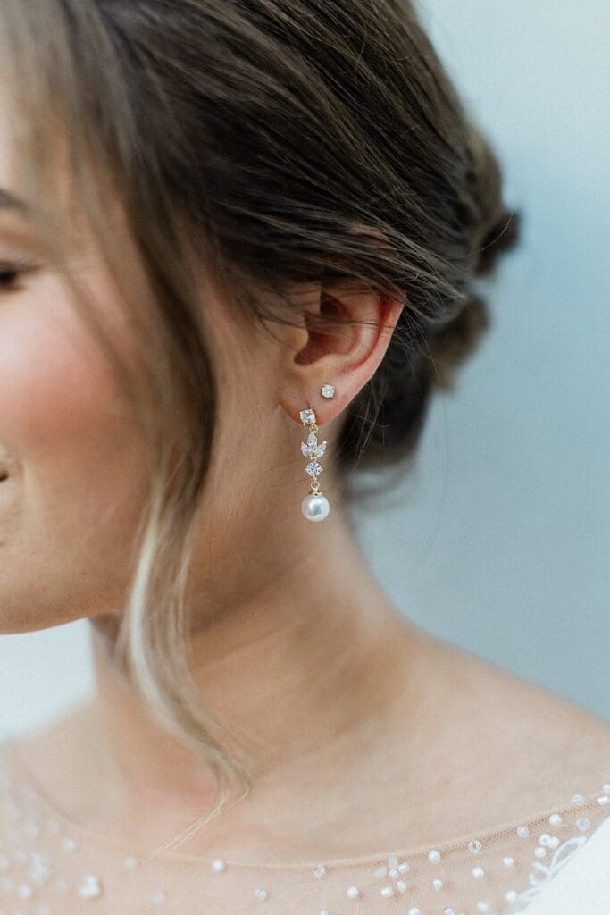 Close up of brides dangling pearl earrings during her bridal portraits at Iron Manor